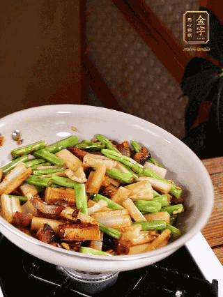 油熱下蒜末、干辣椒、醬肉煸炒出香味，依次下藕條、豆角翻炒均勻